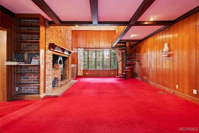 unfurnished living room with a fireplace, wooden walls, carpet, and beam ceiling
