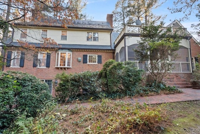 back of property featuring a chimney and brick siding