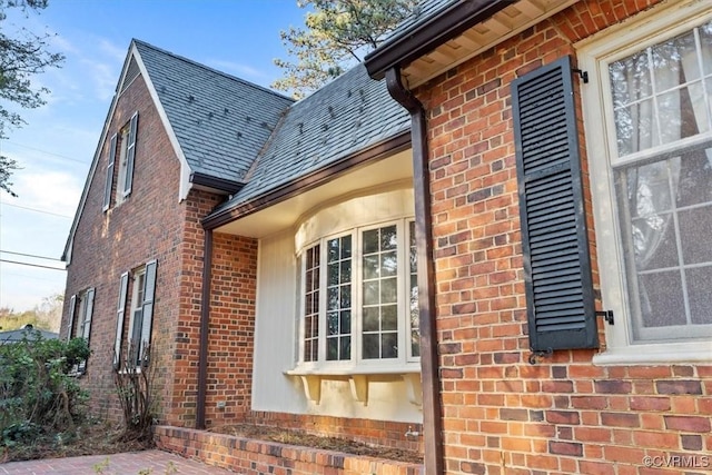 view of side of property featuring brick siding and a high end roof