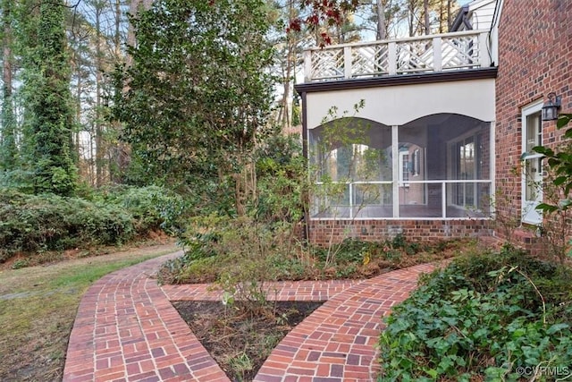 view of yard featuring a sunroom and a balcony