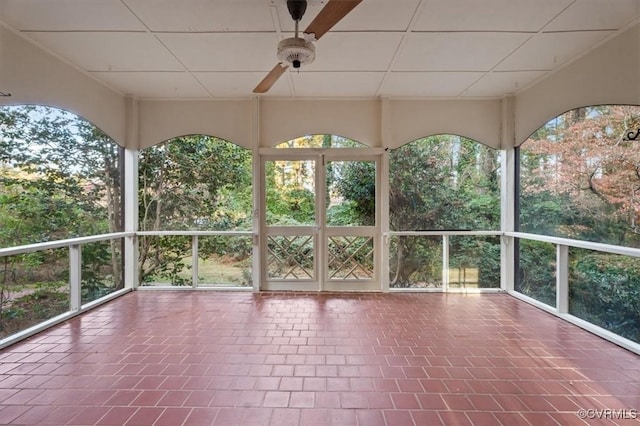 unfurnished sunroom with ceiling fan and tile patterned flooring
