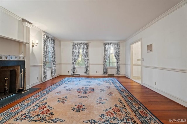 unfurnished living room featuring wood finished floors, a fireplace with raised hearth, and ornamental molding