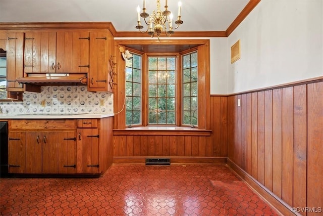 kitchen featuring brown cabinets, backsplash, light countertops, visible vents, and a notable chandelier