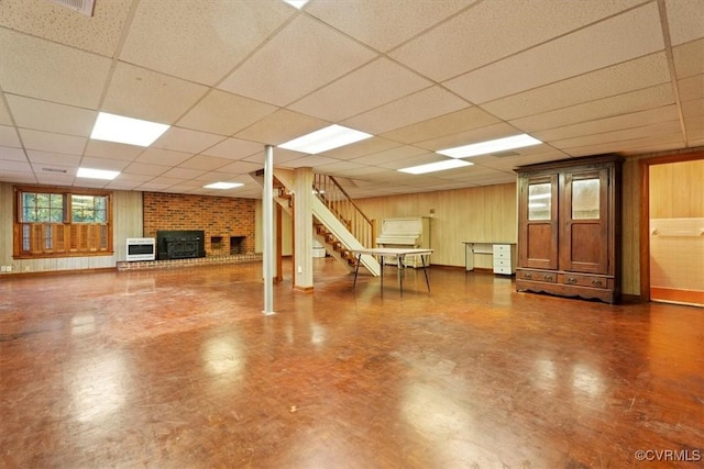 basement featuring wooden walls, stairs, and a drop ceiling