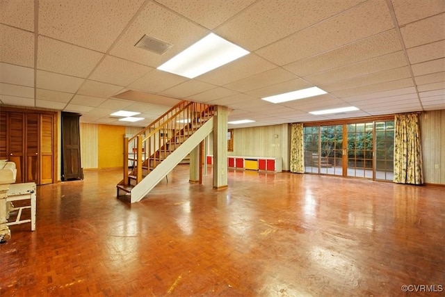 interior space featuring a drop ceiling and wood walls