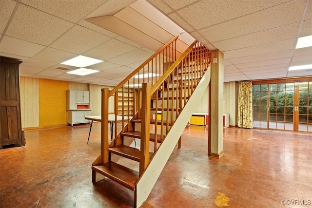stairway with a paneled ceiling and baseboards