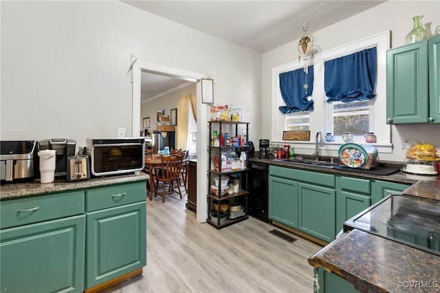 kitchen featuring light wood-style flooring, a sink, dark countertops, visible vents, and black dishwasher