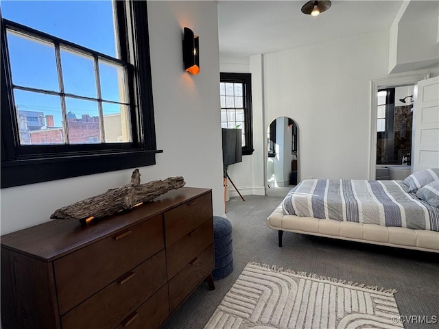 carpeted bedroom featuring arched walkways