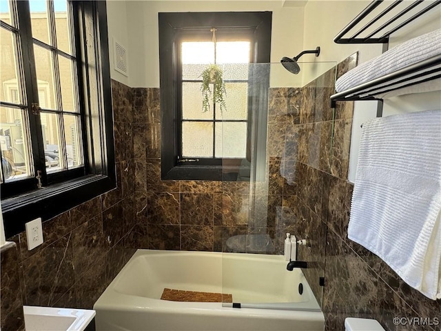 bathroom featuring visible vents, toilet, tile walls, and shower / bathtub combination