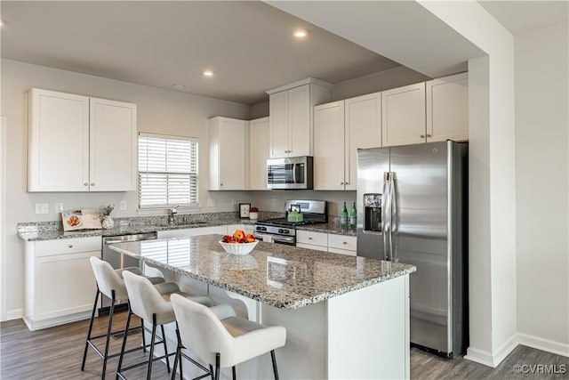6328 Gossamer Aly, Moseley, VA 23120 - kitchen featuring baseboards, a kitchen island, light stone countertops, stainless steel appliances, and wood finished floors