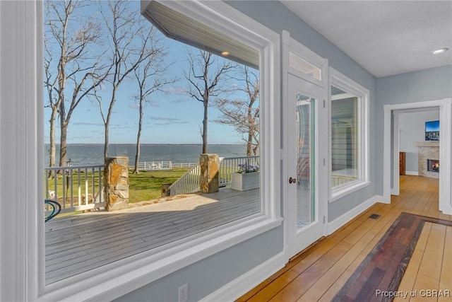 289 Oyster Shell Rd, Laneview, VA 22560 - doorway with a water view, hardwood / wood-style flooring, baseboards, a warm lit fireplace, and healthy amount of natural light