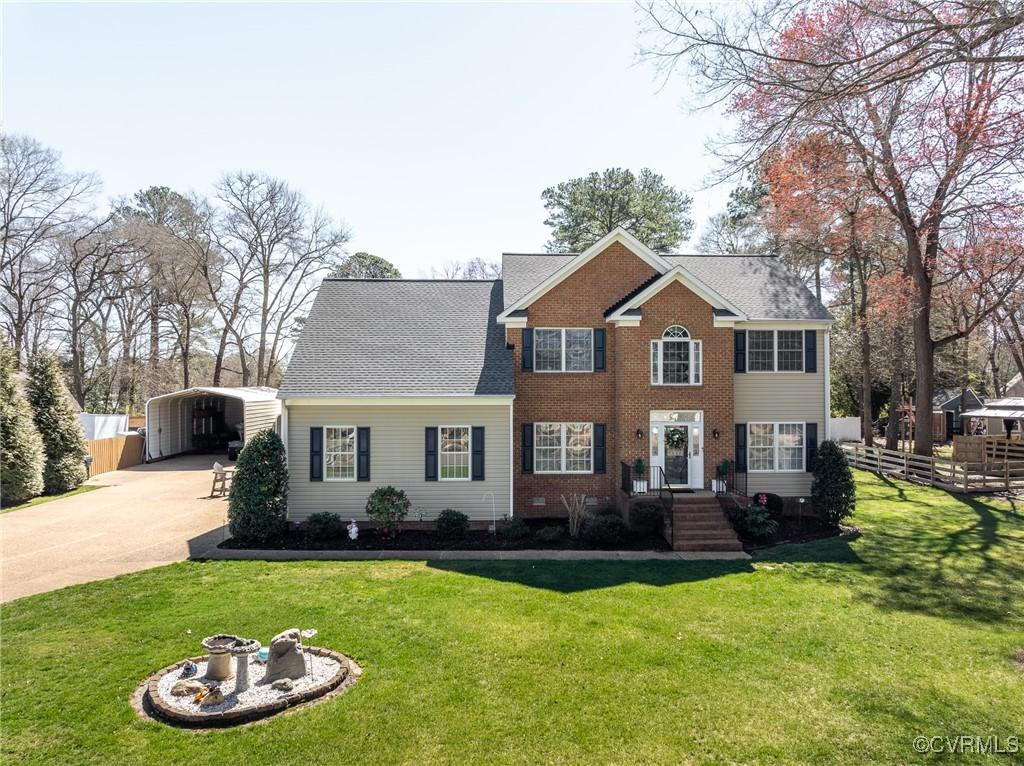 colonial inspired home with a front lawn, driveway, fence, and a detached carport