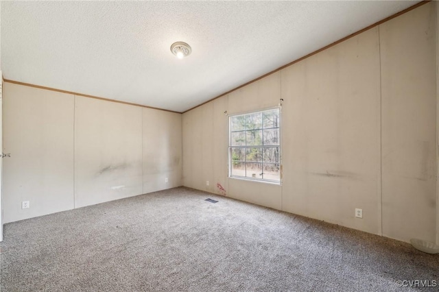 carpeted spare room featuring visible vents, a textured ceiling, and vaulted ceiling