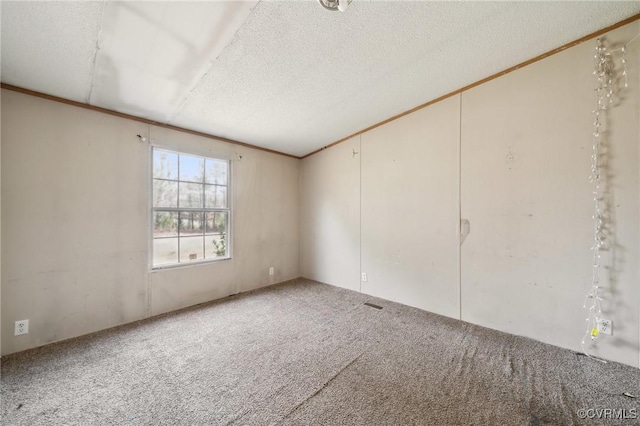 empty room featuring a textured ceiling, carpet flooring, and crown molding