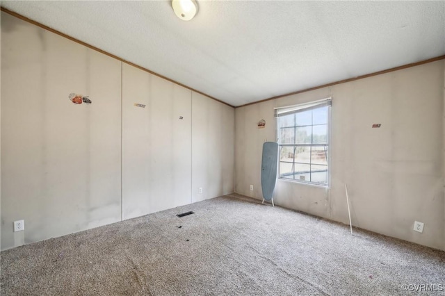 carpeted spare room with crown molding, visible vents, and a textured ceiling