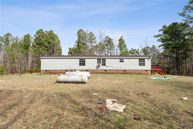 rear view of property with crawl space and a lawn