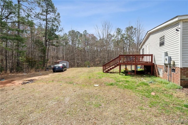 view of yard featuring stairs, a wooden deck, an outdoor structure, and dirt driveway