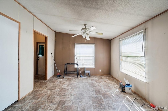 empty room featuring crown molding, a ceiling fan, lofted ceiling, and a textured ceiling