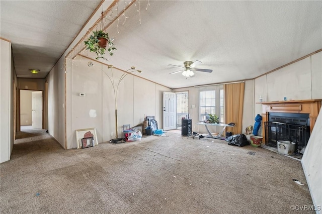 interior space featuring a textured ceiling, a glass covered fireplace, and a ceiling fan