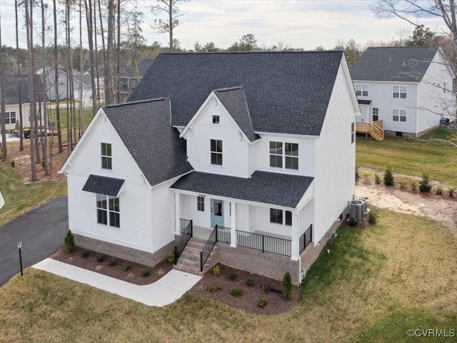 modern farmhouse with central AC, a front lawn, board and batten siding, a shingled roof, and a porch