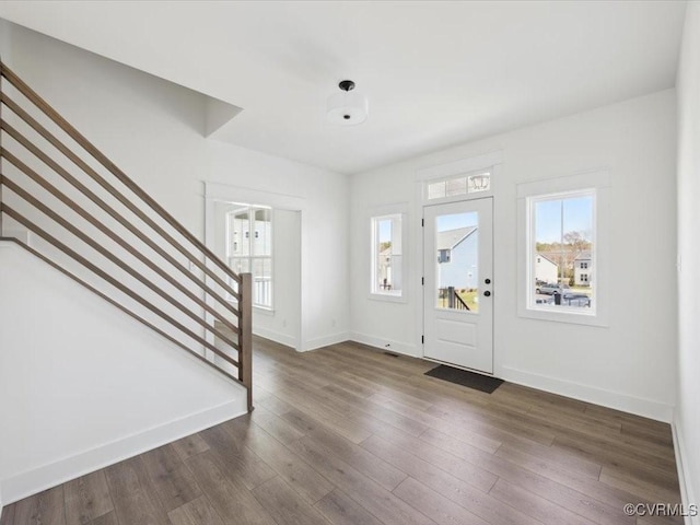 foyer with baseboards, stairway, and dark wood finished floors