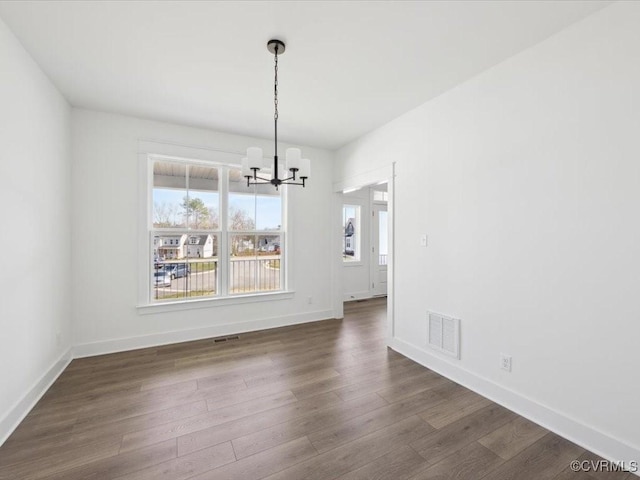 unfurnished dining area featuring baseboards, visible vents, dark wood-type flooring, and a chandelier