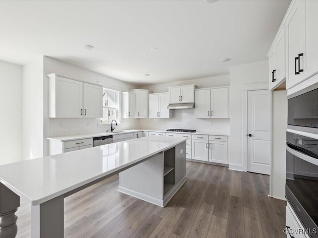 kitchen featuring light countertops, stainless steel appliances, under cabinet range hood, and a center island