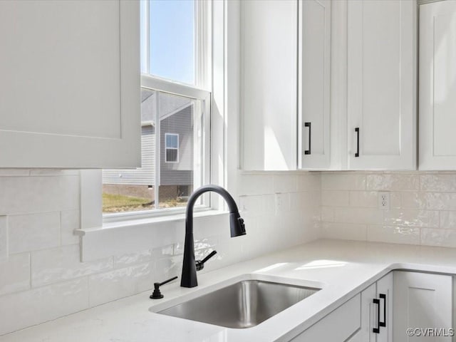 kitchen featuring white cabinetry, light countertops, a sink, and decorative backsplash