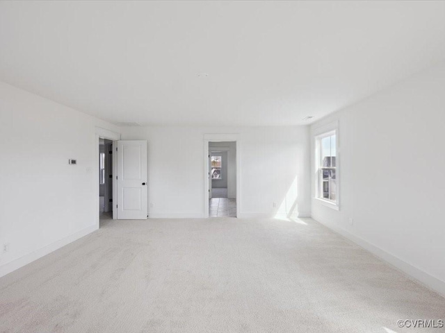 unfurnished room featuring baseboards and light colored carpet