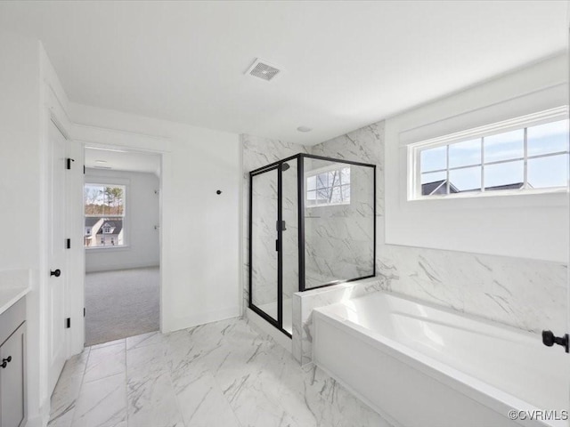 bathroom featuring a marble finish shower, marble finish floor, a wealth of natural light, and visible vents