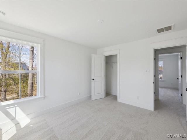 unfurnished bedroom featuring multiple windows, visible vents, and baseboards