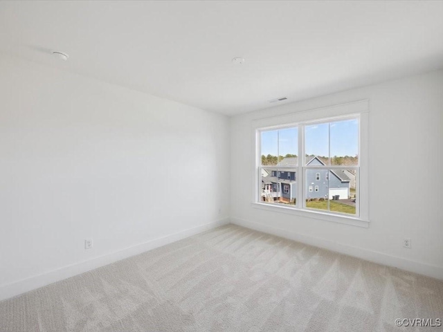empty room with light colored carpet, visible vents, and baseboards