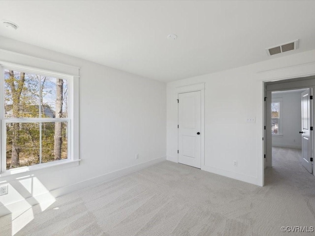 unfurnished room featuring baseboards, visible vents, and a healthy amount of sunlight
