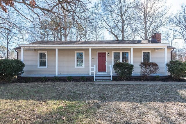 view of front of property with a porch, a front lawn, and a chimney