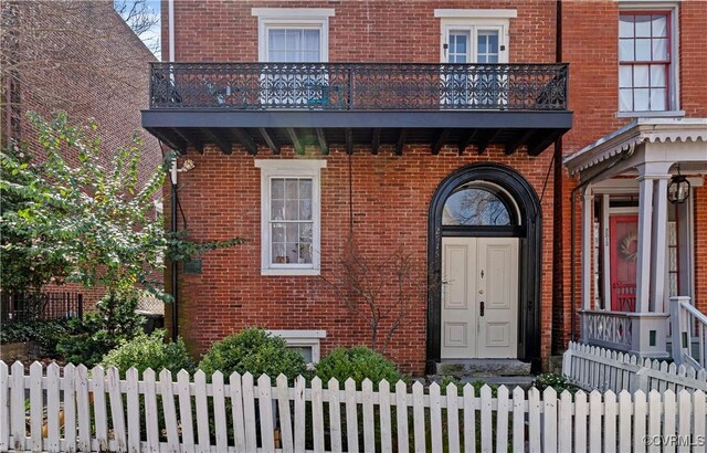 2515 E Grace St, Richmond, VA 23223 - property entrance with a balcony, fence, and brick siding
