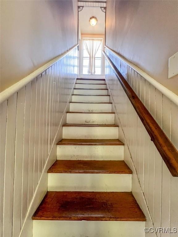 stairway featuring wooden walls and wainscoting