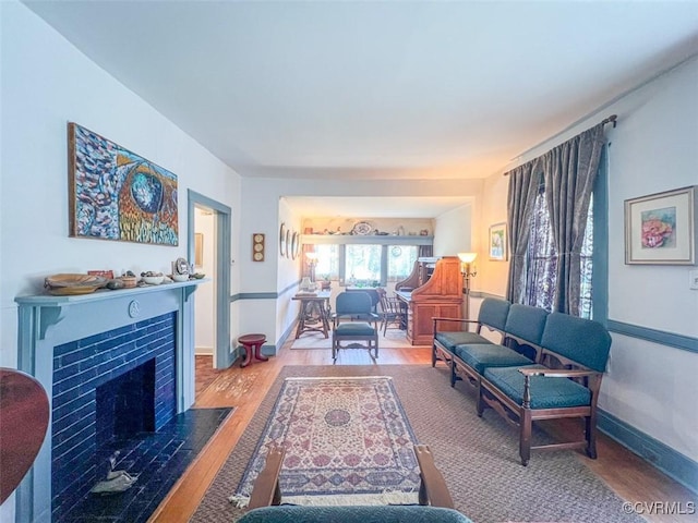 living area featuring a tiled fireplace, wood finished floors, and baseboards
