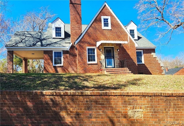 view of front of house featuring a front lawn, brick siding, and a chimney