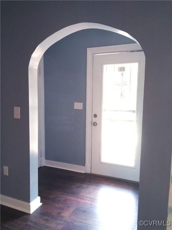 foyer with baseboards, arched walkways, and dark wood-style flooring