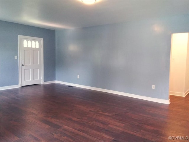 spare room featuring baseboards and dark wood-style floors
