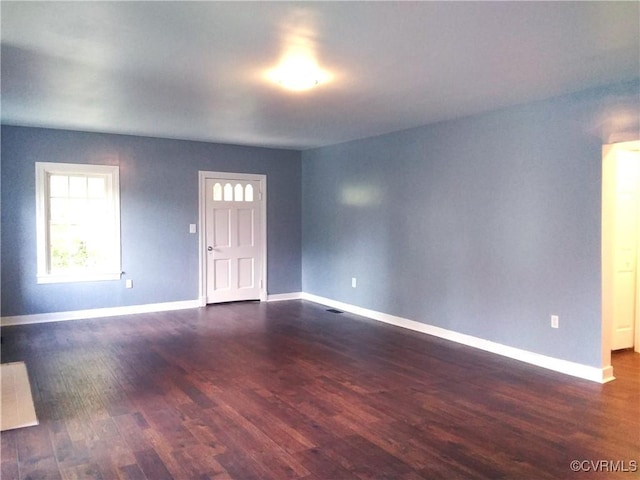 empty room featuring dark wood finished floors and baseboards