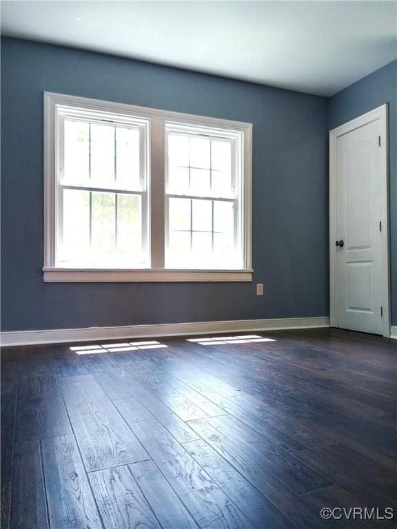 unfurnished room featuring dark wood-style floors and a healthy amount of sunlight