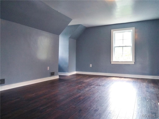 bonus room with baseboards, vaulted ceiling, visible vents, and dark wood-type flooring