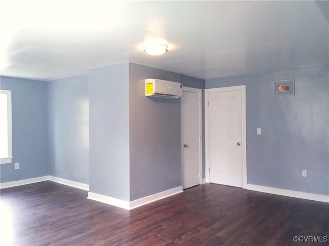spare room featuring baseboards, a wall mounted air conditioner, and dark wood-style floors