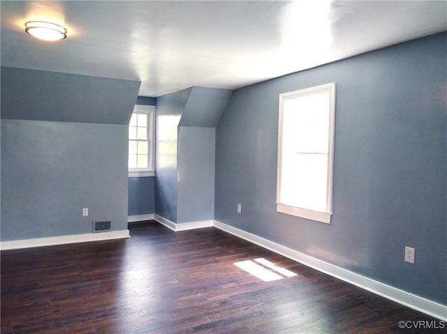 bonus room featuring vaulted ceiling, dark wood-type flooring, visible vents, and baseboards