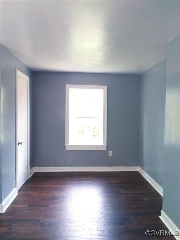 unfurnished room featuring baseboards and dark wood-type flooring
