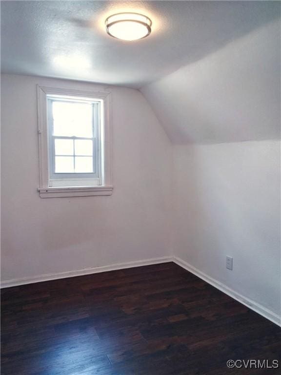 bonus room featuring dark wood finished floors, lofted ceiling, and baseboards