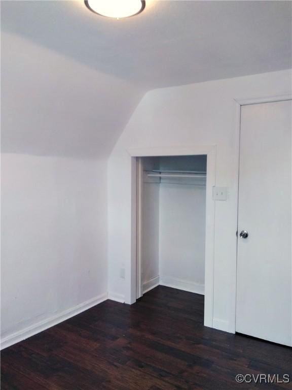 interior space featuring lofted ceiling, baseboards, and dark wood-style flooring