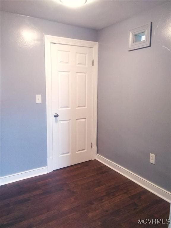 unfurnished room with dark wood finished floors and baseboards