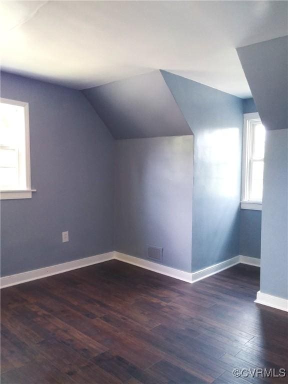 additional living space with dark wood-type flooring, lofted ceiling, and baseboards